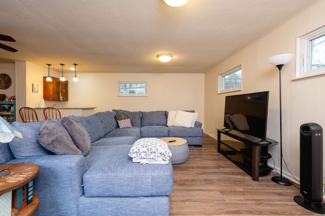 living room with ceiling fan, hardwood / wood-style floors, and a textured ceiling