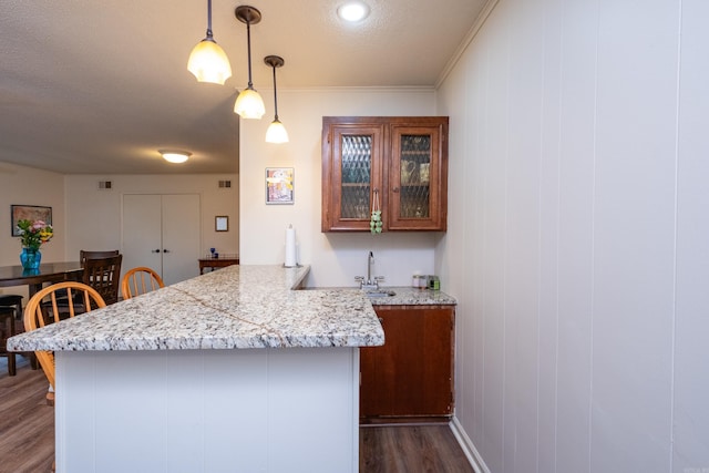 kitchen featuring pendant lighting, a breakfast bar, crown molding, dark hardwood / wood-style flooring, and kitchen peninsula