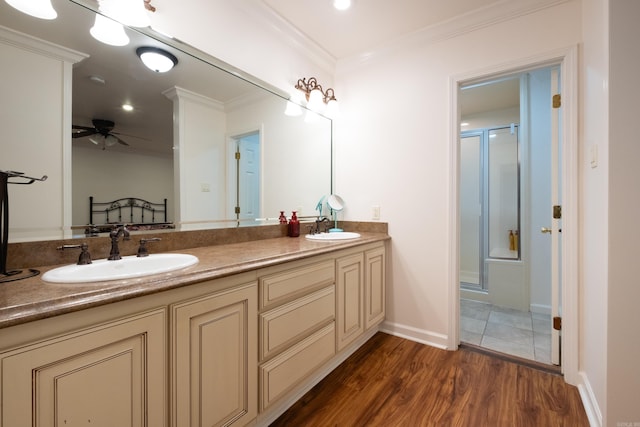 bathroom featuring ceiling fan, crown molding, wood-type flooring, a shower with door, and vanity