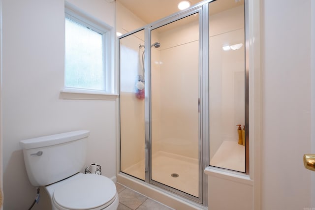 bathroom with tile patterned floors, toilet, and a shower with shower door