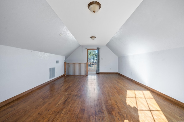 bonus room featuring a textured ceiling, dark hardwood / wood-style floors, and lofted ceiling