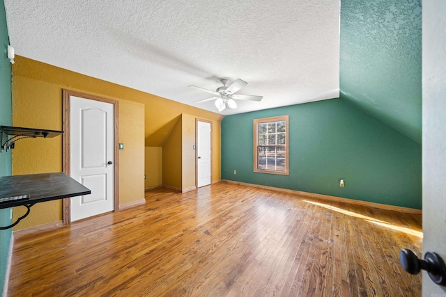 additional living space featuring ceiling fan, wood-type flooring, a textured ceiling, and vaulted ceiling