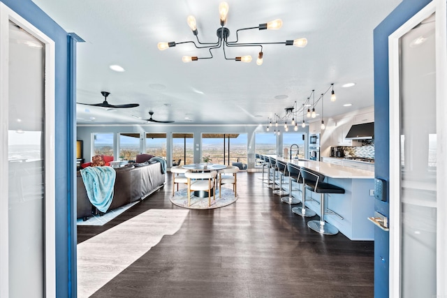 living room featuring ceiling fan with notable chandelier, dark hardwood / wood-style flooring, and sink