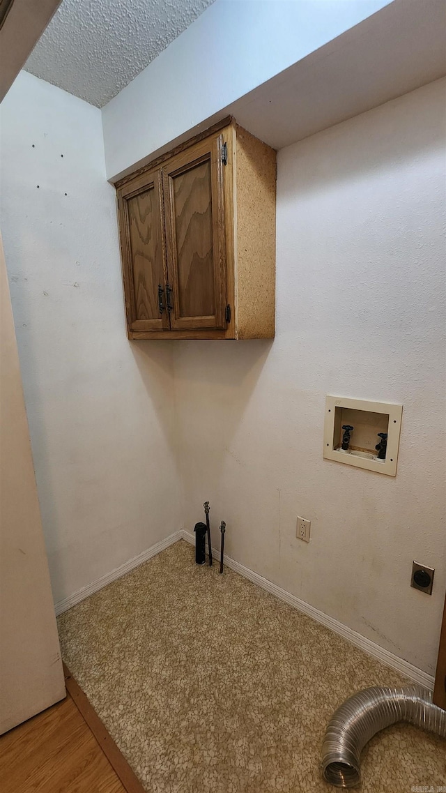 laundry room featuring electric dryer hookup, cabinets, washer hookup, light wood-type flooring, and a textured ceiling