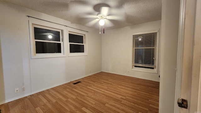 empty room with hardwood / wood-style floors, ceiling fan, and a textured ceiling