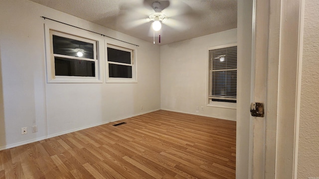 empty room featuring ceiling fan, a textured ceiling, and light hardwood / wood-style flooring