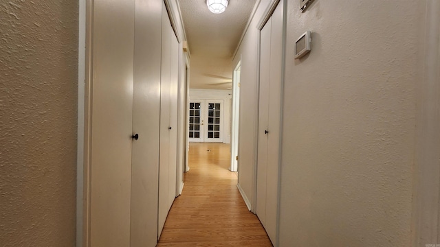 hall with light hardwood / wood-style floors and a textured ceiling