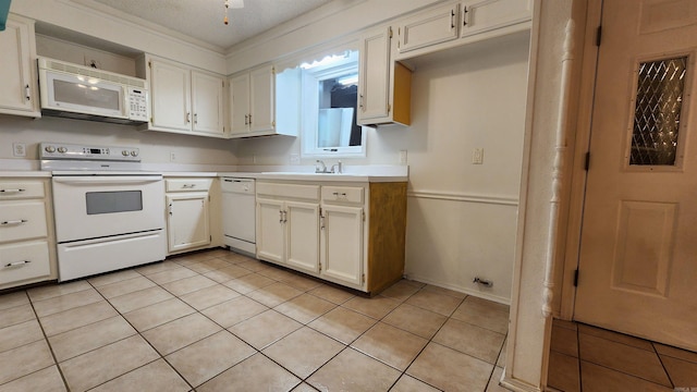 kitchen featuring white appliances, sink, a textured ceiling, light tile patterned flooring, and white cabinetry