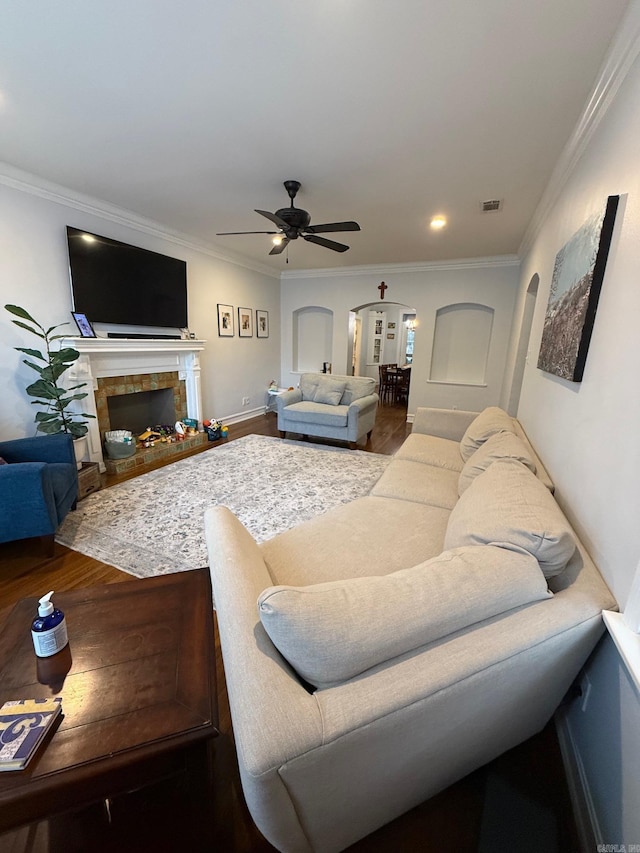 living room with a tile fireplace, ceiling fan, hardwood / wood-style floors, and ornamental molding