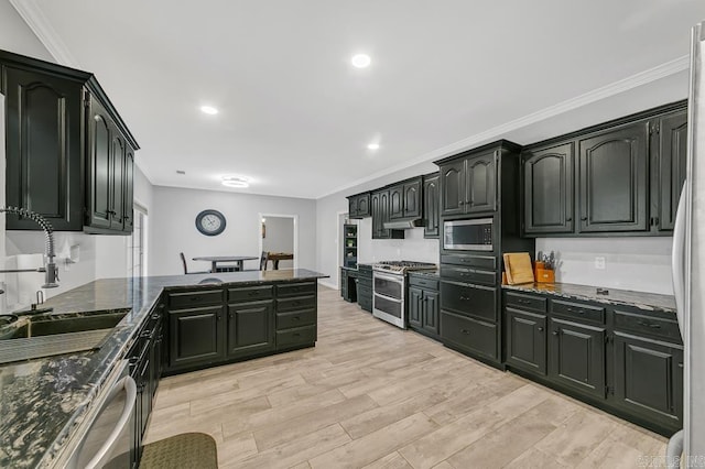 kitchen featuring appliances with stainless steel finishes, light wood-type flooring, crown molding, sink, and dark stone countertops