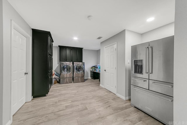 clothes washing area with cabinets, separate washer and dryer, and light hardwood / wood-style floors