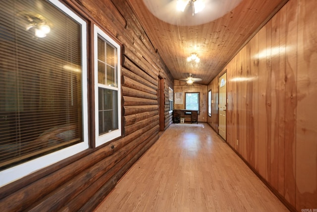 hallway with wooden walls, light hardwood / wood-style flooring, log walls, and wooden ceiling