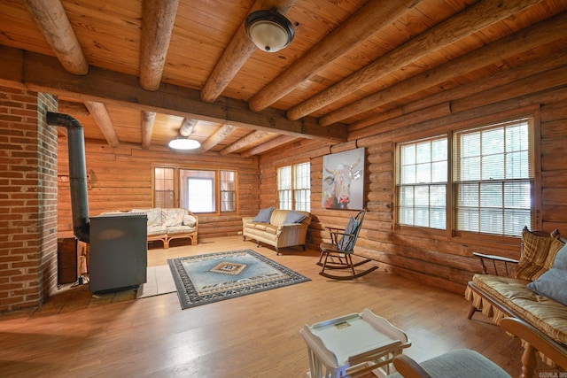 sitting room with a wood stove, rustic walls, plenty of natural light, and wooden ceiling