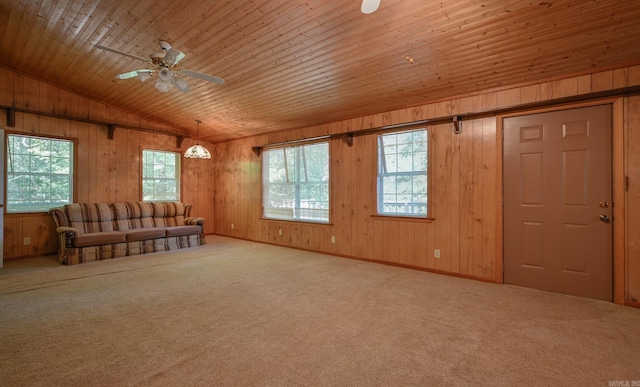 carpeted living room with ceiling fan, wood walls, plenty of natural light, and vaulted ceiling