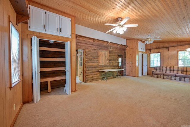 unfurnished living room featuring log walls, ceiling fan, wooden walls, and wood ceiling