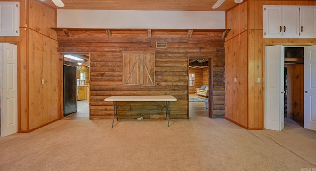 interior space with rustic walls, wood walls, light colored carpet, and wooden ceiling