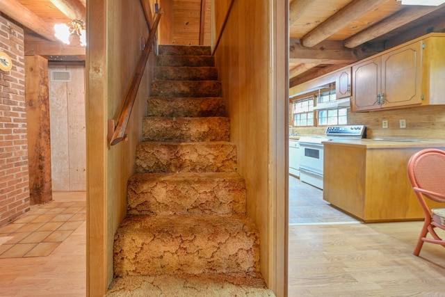 stairs featuring beamed ceiling, wood ceiling, and hardwood / wood-style flooring