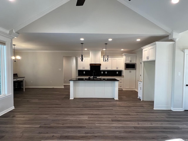 kitchen featuring decorative light fixtures, white cabinetry, stainless steel microwave, and lofted ceiling