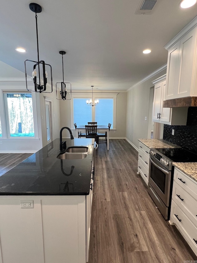 kitchen with white cabinetry, stainless steel range, dark stone counters, a chandelier, and a center island with sink