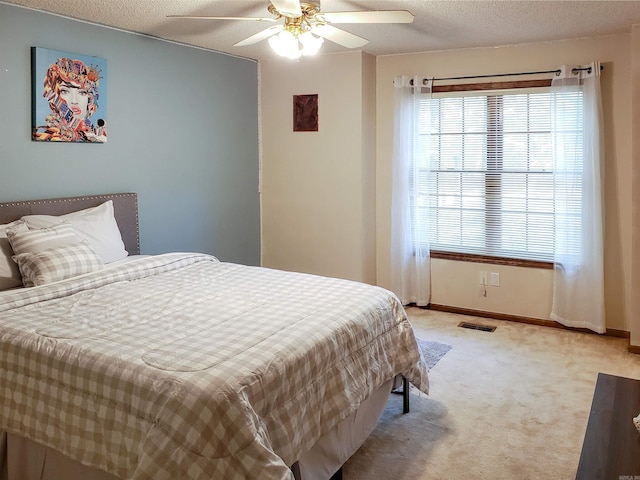 bedroom featuring ceiling fan, light carpet, and a textured ceiling