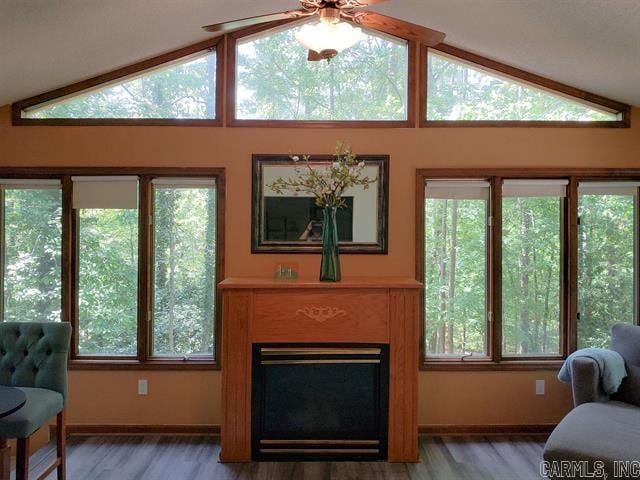 living room with a wealth of natural light, ceiling fan, vaulted ceiling, and hardwood / wood-style flooring