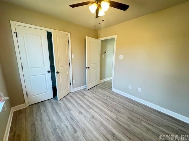 unfurnished bedroom with ceiling fan, light wood-type flooring, and a closet