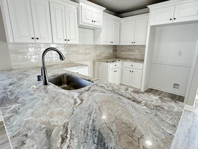 kitchen with white cabinets, light stone counters, and sink