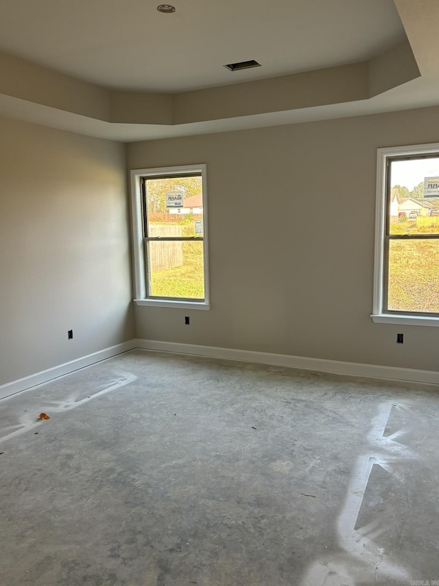 spare room with a tray ceiling and plenty of natural light