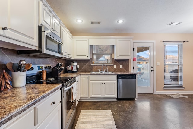 kitchen with white cabinetry, sink, tasteful backsplash, dark stone countertops, and appliances with stainless steel finishes