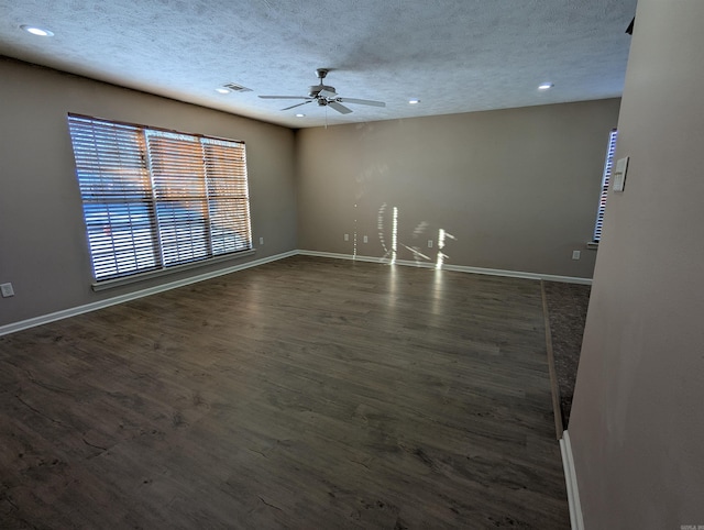 unfurnished room with ceiling fan, dark wood-type flooring, and a textured ceiling