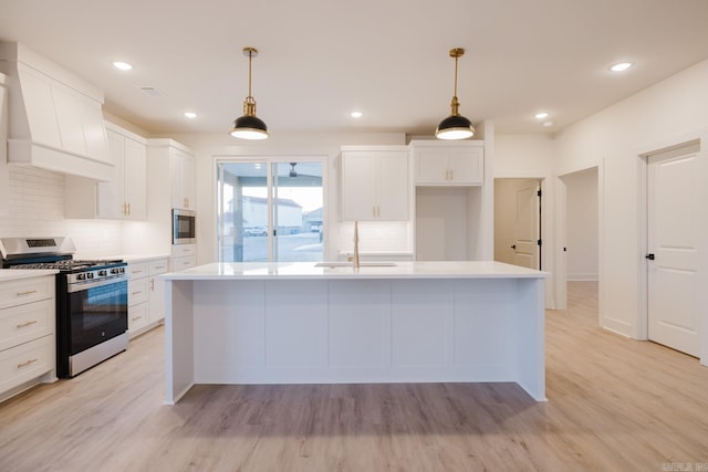 kitchen featuring white cabinetry, sink, light hardwood / wood-style floors, a kitchen island with sink, and appliances with stainless steel finishes