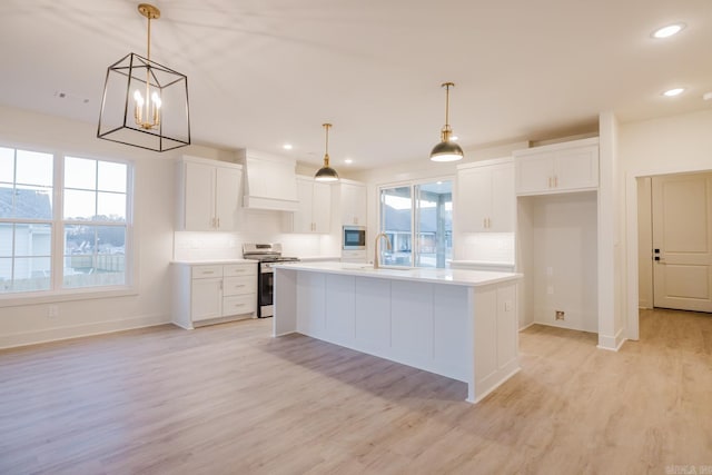 kitchen featuring premium range hood, white cabinetry, an island with sink, and stainless steel appliances