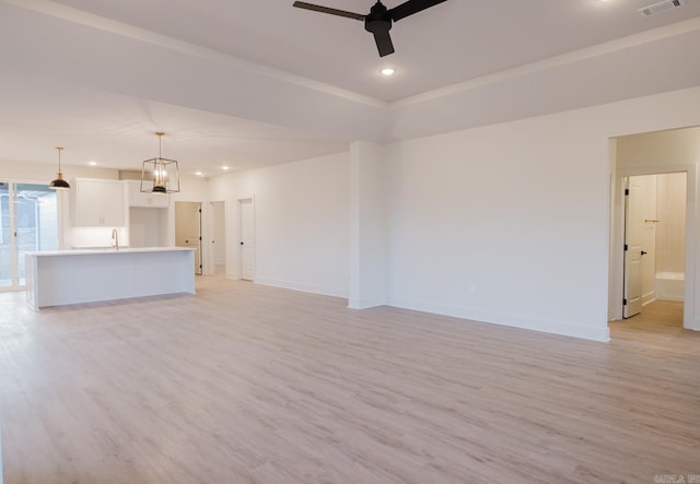 unfurnished living room with ceiling fan, light hardwood / wood-style flooring, and sink