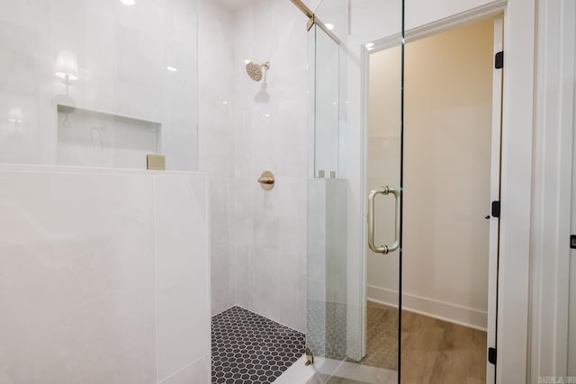 bathroom featuring a shower with shower door and wood-type flooring