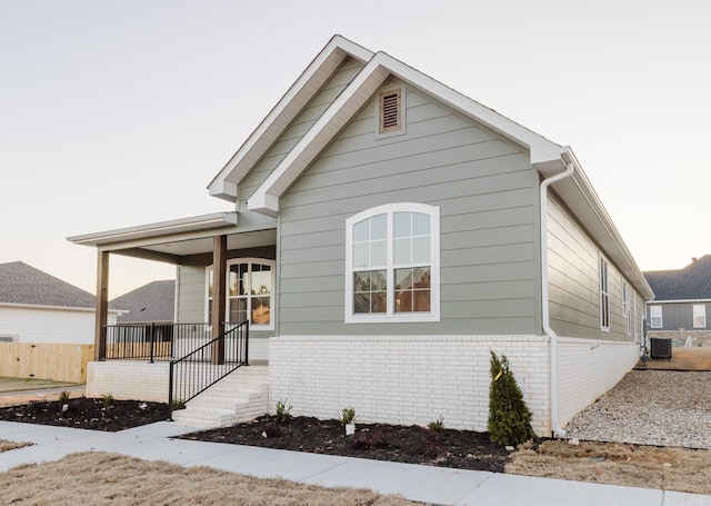 bungalow-style home with central air condition unit and covered porch