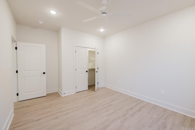 unfurnished bedroom featuring ceiling fan, a closet, and light wood-type flooring