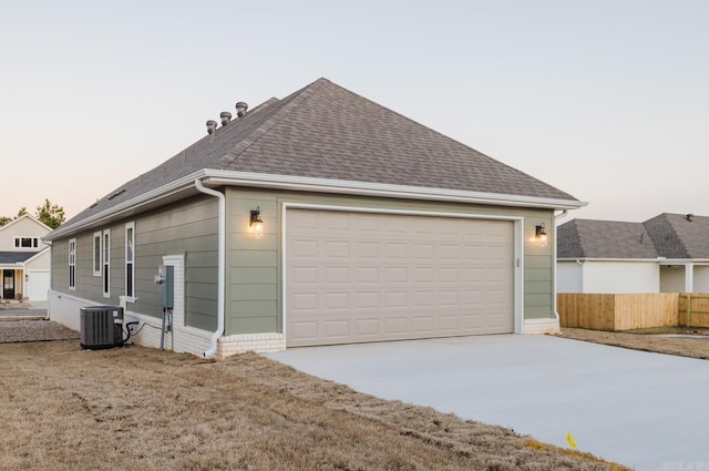 property exterior at dusk with central AC unit and a garage