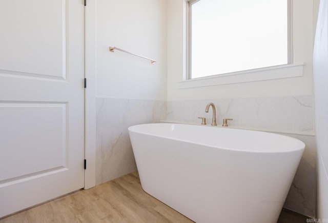 bathroom featuring wood-type flooring and a tub to relax in