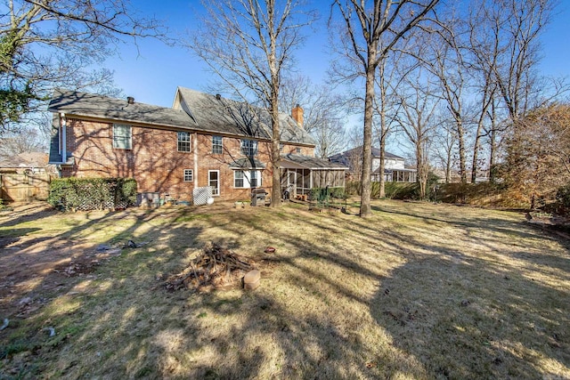 rear view of house with a yard and a sunroom