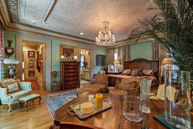 bedroom with a notable chandelier, crown molding, and light hardwood / wood-style flooring