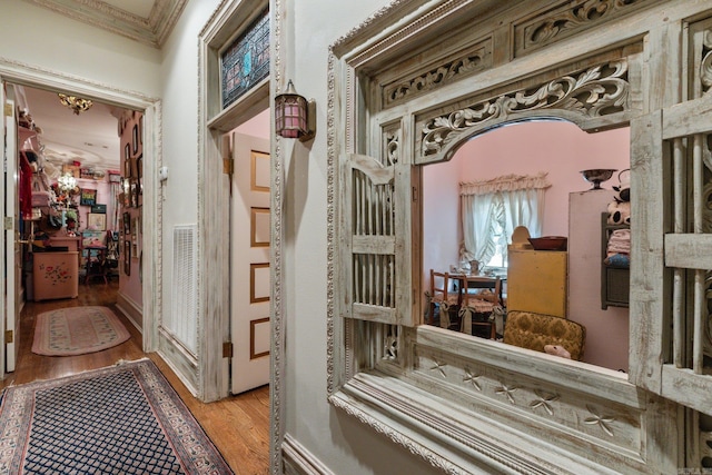 corridor featuring ornamental molding and light hardwood / wood-style flooring