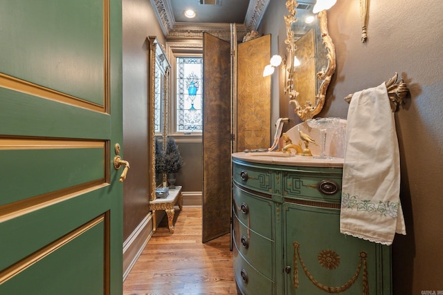 bathroom with vanity, wood-type flooring, and crown molding