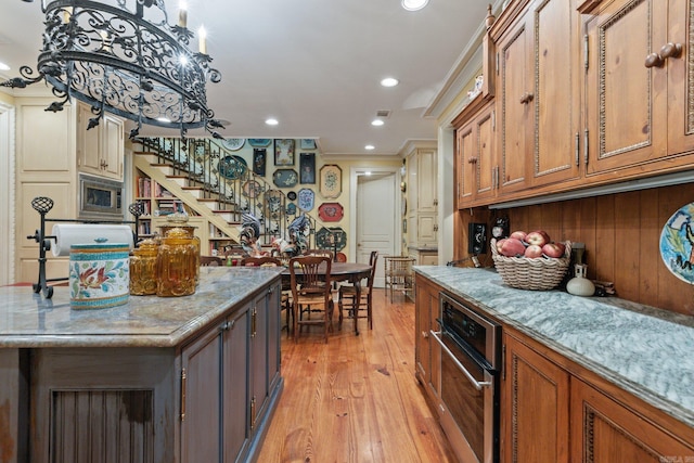 kitchen with light stone countertops, a center island, light hardwood / wood-style floors, and crown molding