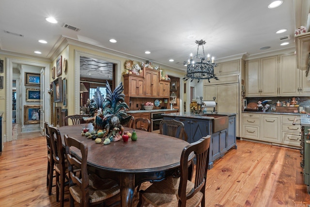 kitchen featuring a kitchen island, cream cabinetry, decorative light fixtures, and light wood-type flooring