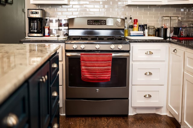 kitchen with white cabinetry, stainless steel gas range, dark hardwood / wood-style flooring, backsplash, and dark stone countertops