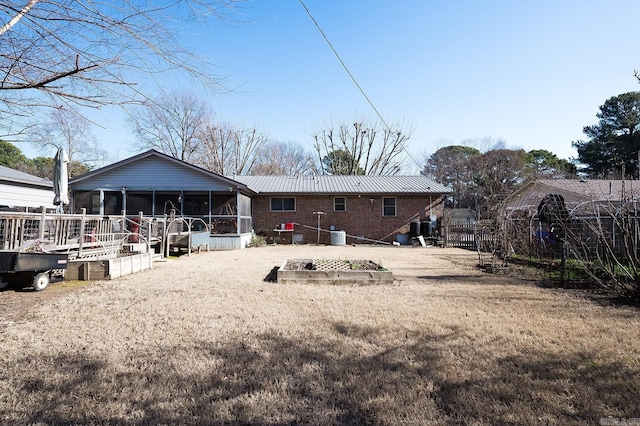 back of property with a sunroom and a lawn