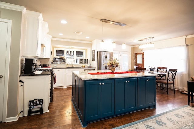 kitchen with stainless steel appliances, blue cabinetry, pendant lighting, a center island, and white cabinetry