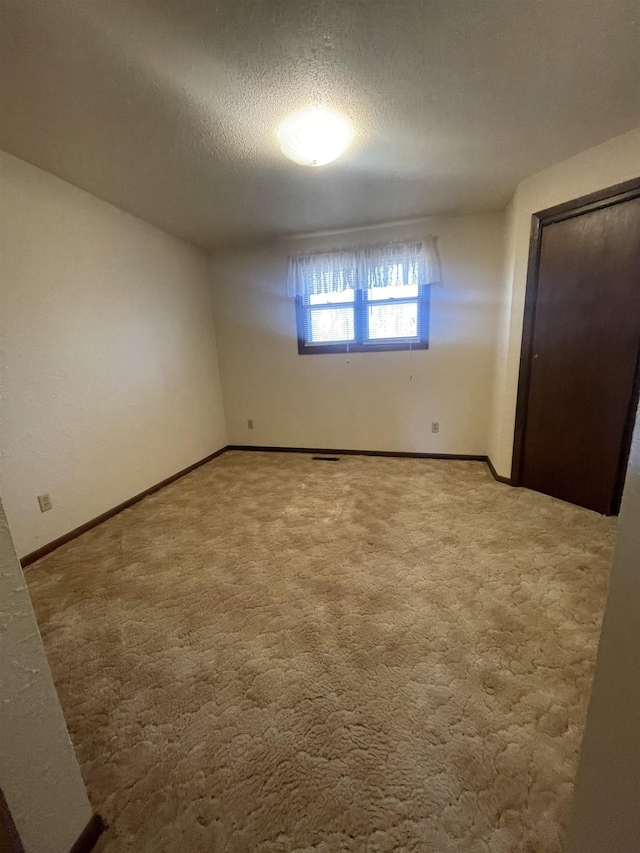 unfurnished bedroom with light colored carpet and a textured ceiling