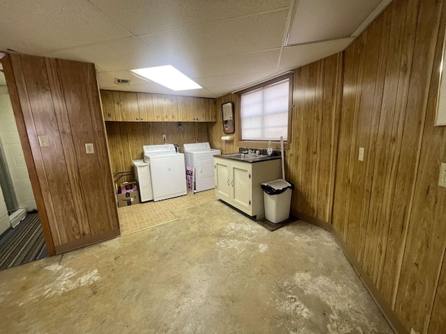 laundry room featuring separate washer and dryer, wooden walls, sink, and cabinets