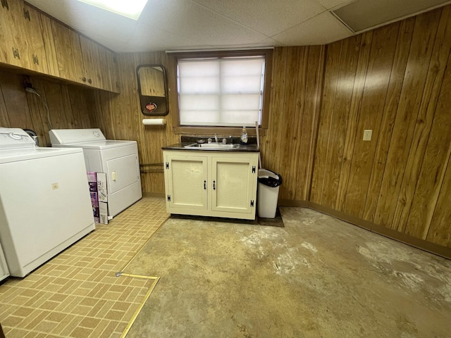 washroom featuring washer and dryer, cabinets, sink, and wooden walls